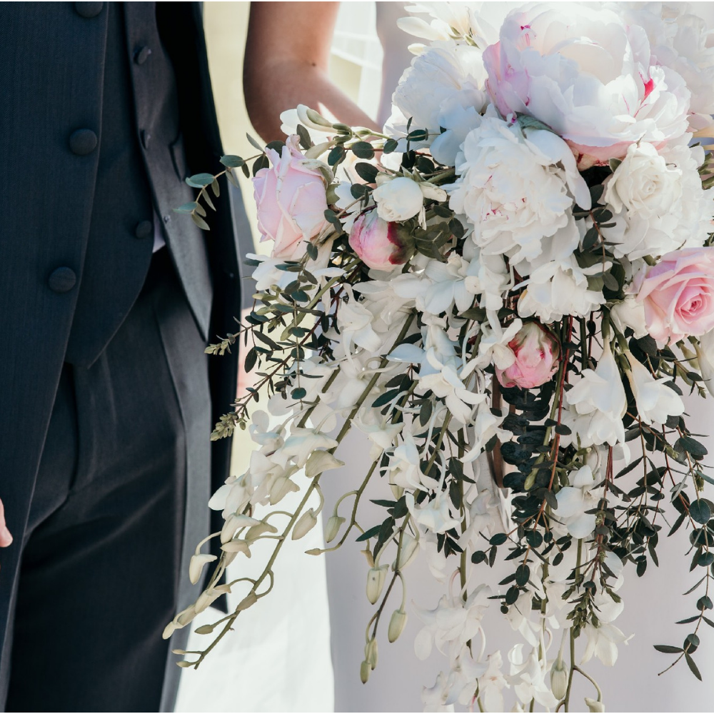 Extreme close up of a bride carrying a bouquet of pink and cream flowers